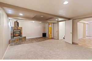 Finished below grade area featuring carpet, recessed lighting, a tile fireplace, stairway, and arched walkways
