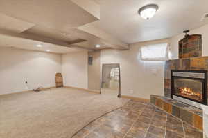 Unfurnished living room with a tile fireplace, a textured ceiling, recessed lighting, carpet floors, and tile patterned flooring