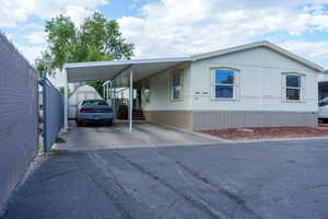 Manufactured / mobile home with a storage unit, driveway, and an attached carport