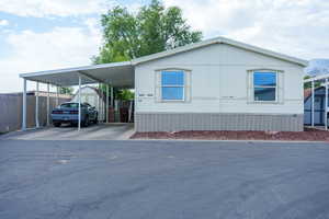 Manufactured / mobile home with a storage shed, concrete driveway, and an attached carport