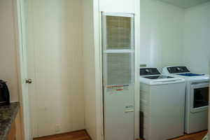 Laundry room featuring a heating unit, dark wood-type flooring, and washer and dryer