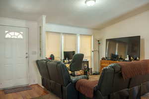 Living room featuring wood finished floors, ornamental molding, and a textured ceiling