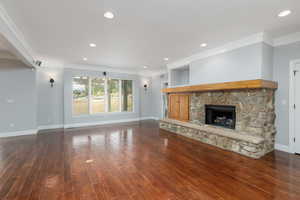 Unfurnished living room with crown molding, a fireplace, recessed lighting, and dark wood-style floors