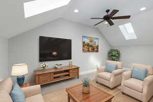 Carpeted living room featuring a skylight, lofted ceiling, and ceiling fan