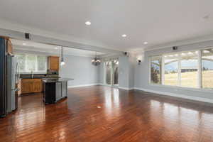 Unfurnished living room featuring crown molding, dark wood-type flooring, recessed lighting, and a chandelier