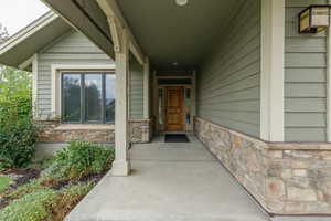 Doorway to property featuring stone siding and covered porch