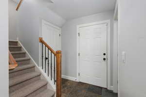 Entryway featuring dark stone finish floors and stairway
