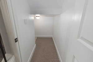 Corridor with light colored carpet and baseboards
