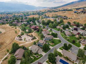 Aerial view of property and surrounding area featuring nearby suburban area and a mountain backdrop