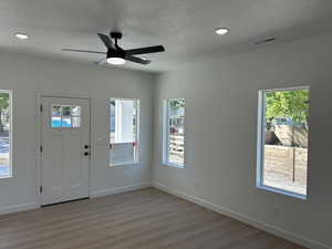 Foyer with plenty of natural light, a textured ceiling, wood finished floors, ceiling fan, and recessed lighting