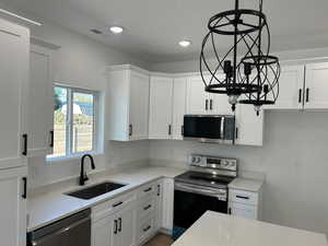 Kitchen featuring LG stainless steel appliances, white cabinets, light stone countertops, a textured ceiling, and hanging light fixtures