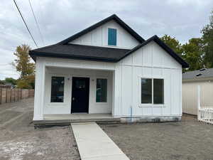 Modern farmhouse with board and batten siding, covered porch, and a shingled roof