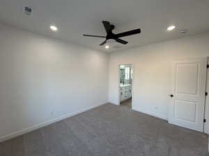 Unfurnished bedroom featuring dark colored carpet, ensuite bathroom, ceiling fan, and recessed lighting