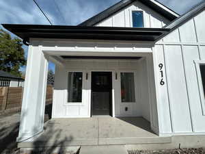 View of exterior entry with board and batten siding and a porch