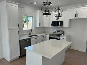 Kitchen with appliances with stainless steel finishes, a center island, white cabinets, and recessed lighting