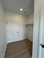 Laundry area featuring wood finished floors, recessed lighting, and washer hookup