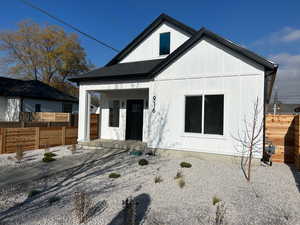 View of front of house featuring covered porch, roof with shingles, and board and batten siding