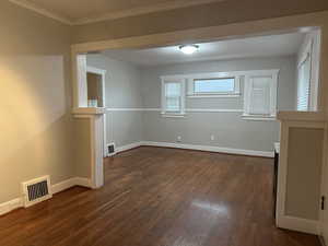 Spare room with dark wood-type flooring and crown molding