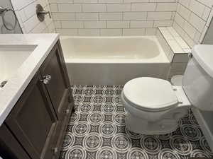 Full bath featuring vanity, light tile patterned flooring, and washtub / shower combination