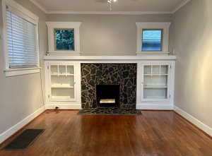 Unfurnished living room featuring a fireplace, crown molding, dark wood-style flooring, and ceiling fan