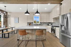 Kitchen with stainless steel appliances, backsplash, pendant lighting, a kitchen island, and light wood-style floors