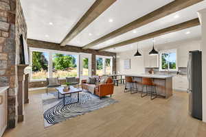 Living room featuring beamed ceiling, light wood-style floors, recessed lighting, a chandelier, and a fireplace