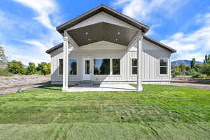 Rear view of house featuring a patio area, a lawn, and a mountain view