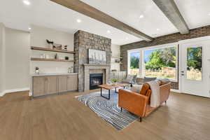 Living area featuring beamed ceiling, light wood-type flooring, recessed lighting, a fireplace, and brick wall