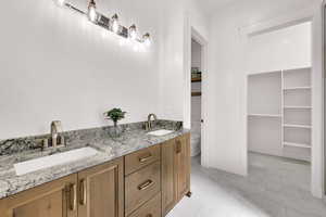 Full bathroom featuring double vanity, light tile patterned floors, and a spacious closet