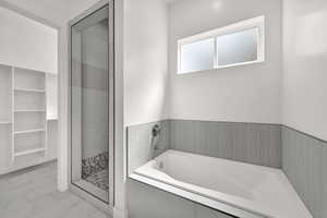 Bathroom with a bath, a stall shower, and a spacious closet