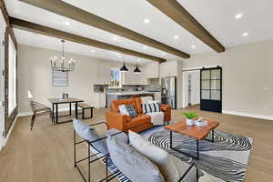 Living area with a barn door, recessed lighting, beamed ceiling, light wood-style flooring, and a chandelier
