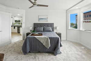 Bedroom featuring light carpet, ornamental molding, and ceiling fan