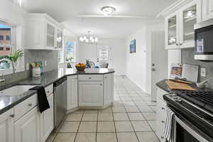 Kitchen with tasteful backsplash, glass insert cabinets, appliances with stainless steel finishes, and a peninsula