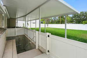 Fenced backyard featuring a sunroom and a gate