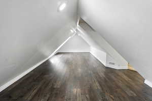 Bonus room with dark wood-type flooring and vaulted ceiling