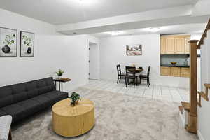 Living area with light tile patterned flooring, stairway, light carpet, and a textured ceiling