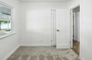 Unfurnished room featuring light colored carpet and ornamental molding