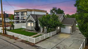 View of front of home featuring roof with shingles, concrete driveway, a garage, a fenced front yard, and a chimney