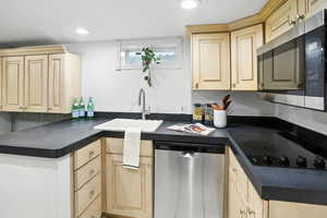 Kitchen featuring appliances with stainless steel finishes, dark countertops, light brown cabinets, recessed lighting, and decorative backsplash