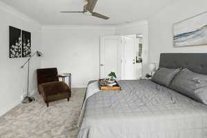 Bedroom with ornamental molding, carpet flooring, and a ceiling fan