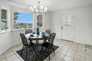 Dining room featuring healthy amount of natural light, light tile patterned floors, and a chandelier