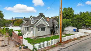 View of front of home with roof with shingles, a fenced front yard, and a chimney