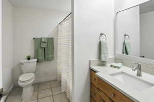 Full bath with vanity, light tile patterned floors, and a shower with curtain