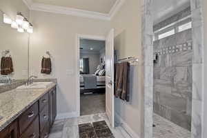 Ensuite bathroom featuring crown molding, vanity, a walk in shower, and light marble finish floors