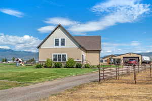 View of front of house featuring an outdoor structure, a mountain view, stone siding, a playground, and stucco siding