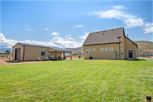 Back of house with a mountain view, an outbuilding, a patio area, and stucco siding