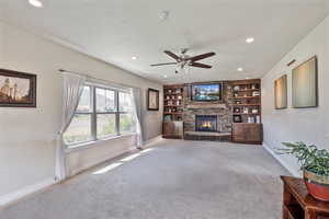 Living area featuring built in shelves, carpet, ceiling fan, recessed lighting, and a fireplace