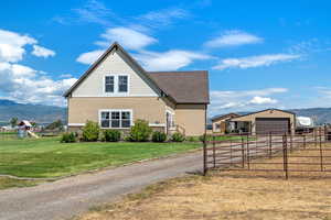 View of side of property with a mountain view, stone siding, an outdoor structure, stucco siding, and a playground