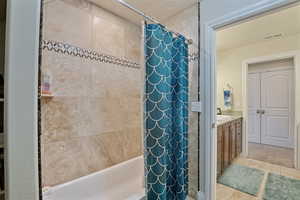 Full bath featuring shower / tub combo with curtain, vanity, and light tile patterned floors