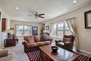 Living area featuring carpet, healthy amount of natural light, recessed lighting, ceiling fan, and a textured ceiling